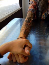 Cropped image of friends holding hands at table