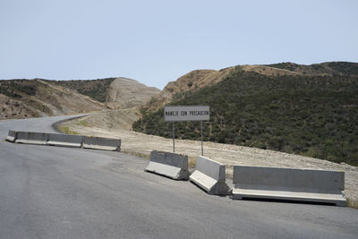 Road sign by mountain against clear sky