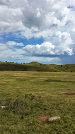 Scenic view of grassy field against cloudy sky