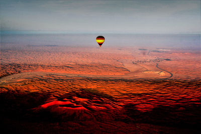 Hot air balloons flying over landscape during sunset