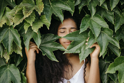 Woman with eyes closed amidst leaves