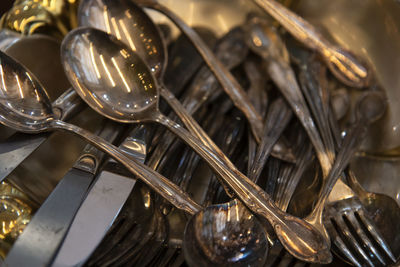 High angle view of steel spoons with forks and table knives