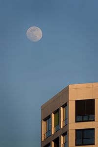 Low angle view of building against clear blue sky and moon