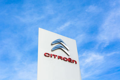 Low angle view of sign against blue sky