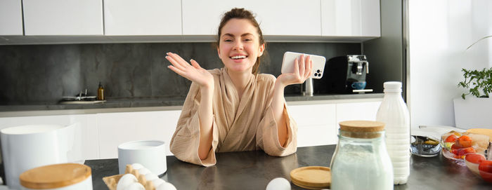 Portrait of young woman sitting in kitchen