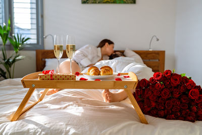 Romantic breakfast in bed on valentine day. couple kissing and having fun in bed celebrating holiday 