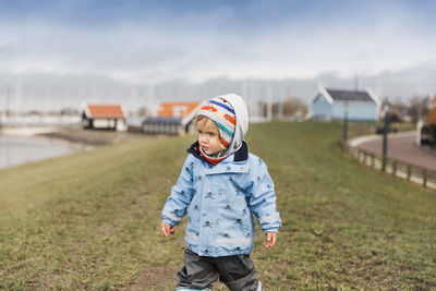 Cute girl wearing warm clothing standing on field