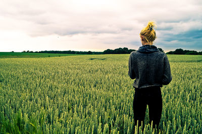 Rear view of young woman standing on wheat field