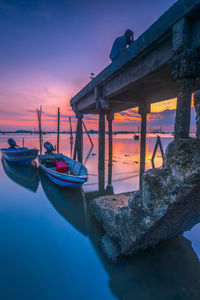 Boat moored on sea against sky during sunset