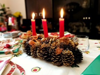 Pine cones by candles on table