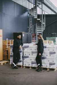 Female and male professional standing by packages at warehouse