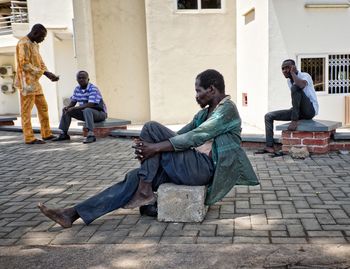Full length of men sitting on footpath