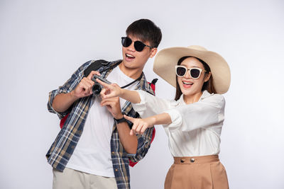 Full length of young man wearing sunglasses against white background