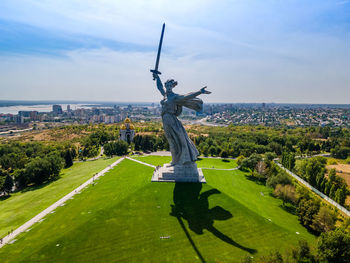 View of statue in city against cloudy sky