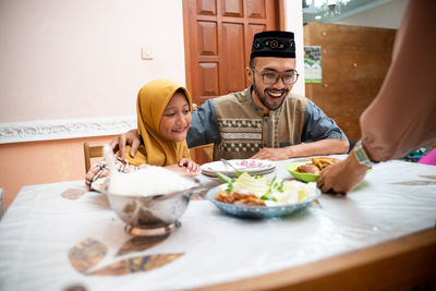 Father and daughter looking at food on table at home