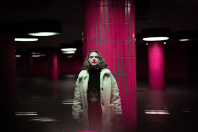 Portrait of woman standing in illuminated garage