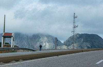 Man on road by mountains against sky