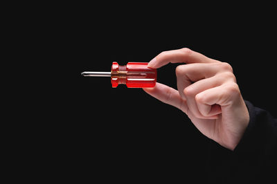 Cropped hand holding syringe against black background