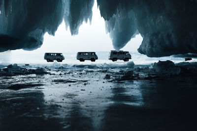 Scenic view of frozen lake with three vans from rock 