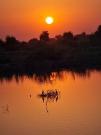 Scenic view of lake against orange sky