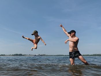 Full length of a child jumping into the sea against the sky