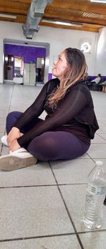 Side view of woman sitting on tiled floor