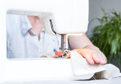 Cropped hand of woman using sewing machine