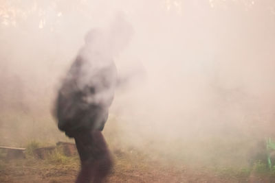 Rear view of man walking on road in foggy field