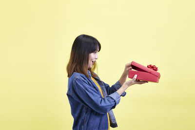 Side view of young woman standing against gray background