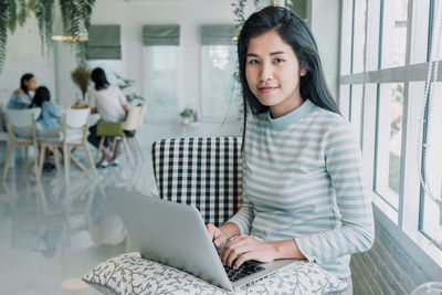 Portrait of smiling young woman using mobile phone