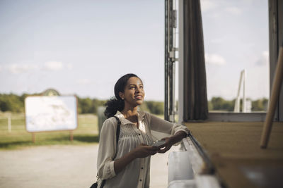 Young businesswoman holding mobile phone while standing by portable office truck