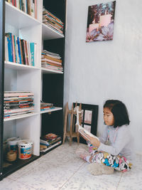 Full length of woman sitting on book at home