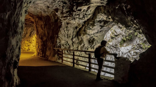 Rear view of woman standing in cave