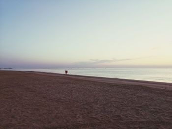 Scenic view of beach against clear sky during sunset