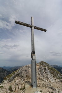 Cross on rock against sky