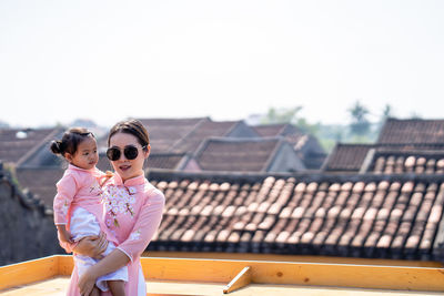Mother and daughter with vietnam culture traditional dress standing at the rooftop in hoi an.