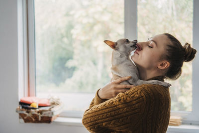 Young woman with dog against window