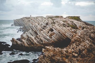 Rock formation on beach against sky