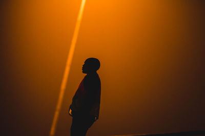 Silhouette man standing against orange sky