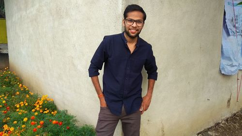 Portrait of young man standing against wall