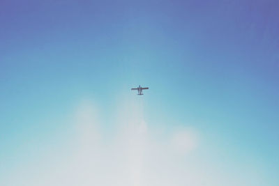 Low angle view of airplane flying against blue sky