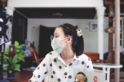Girl looking away while wearing mask at home