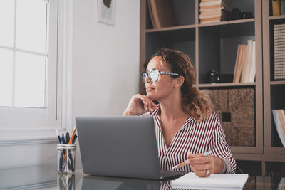 Woman using mobile phone while sitting on table