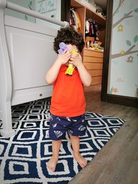 Cute baby boy covering face with toys