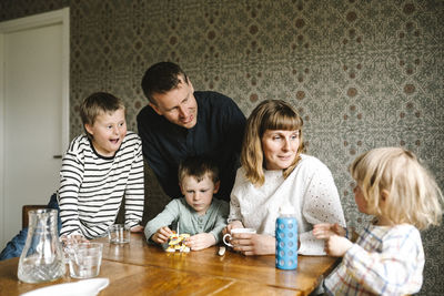 Smiling parents talking with daughter by sons at table