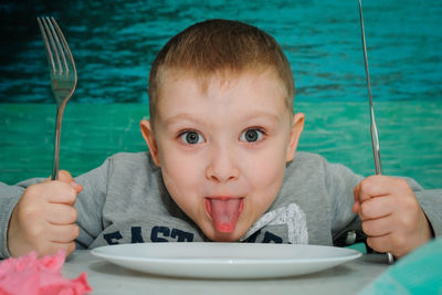 Close-up portrait of boy holding spoon and fork