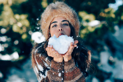 Portrait of woman blowing snow during winter