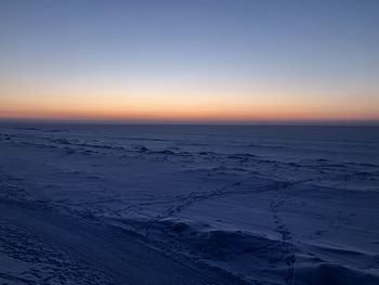 Scenic view of snow covered landscape against clear sky during sunset
