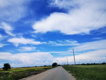 Road amidst field against sky