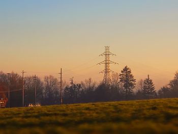 Electricity pylon on field against sky during sunset